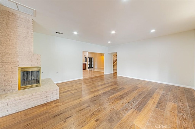 unfurnished living room with a fireplace, wood finished floors, and visible vents