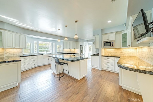 kitchen with glass insert cabinets, decorative backsplash, a kitchen island, and stainless steel appliances