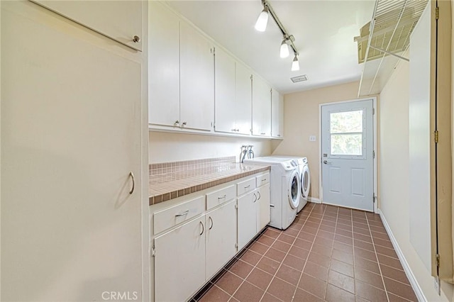 laundry area featuring cabinet space, independent washer and dryer, rail lighting, baseboards, and dark tile patterned floors