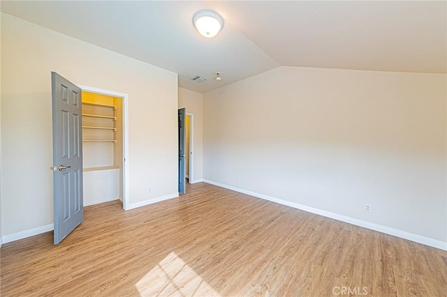 unfurnished bedroom with baseboards, vaulted ceiling, light wood finished floors, and visible vents