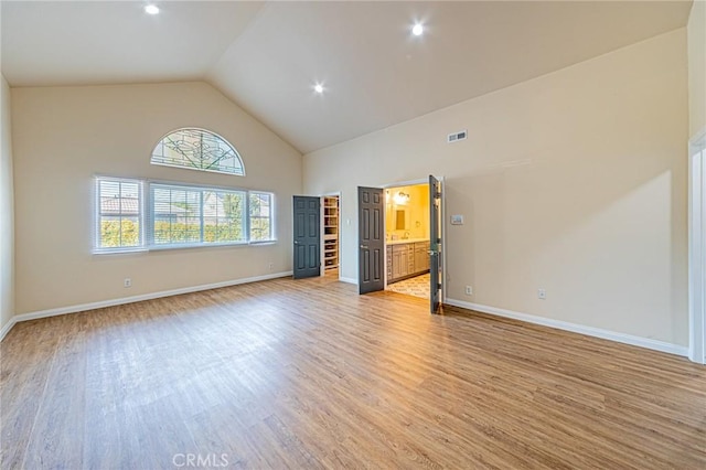 unfurnished living room featuring high vaulted ceiling, recessed lighting, baseboards, light wood-type flooring, and visible vents