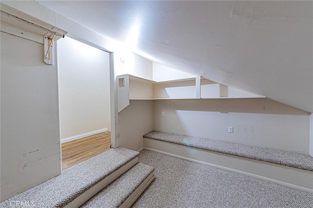 interior space featuring baseboards, carpet, and lofted ceiling
