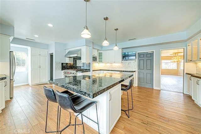 kitchen with glass insert cabinets, a kitchen breakfast bar, stainless steel appliances, and white cabinets