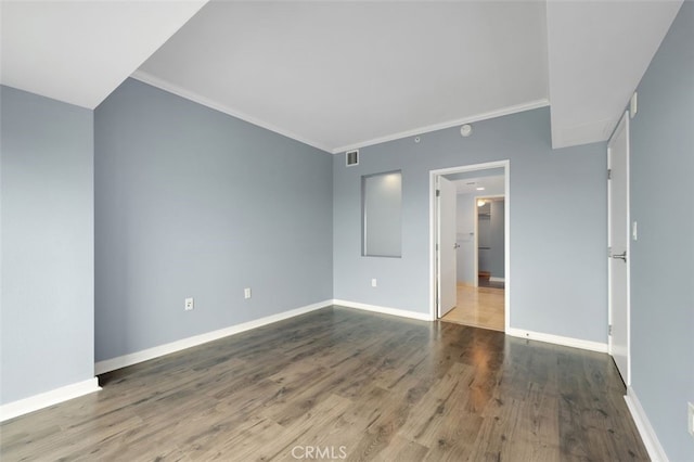 spare room with baseboards, ornamental molding, wood finished floors, and visible vents