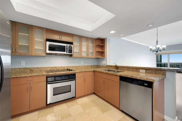 kitchen with pendant lighting, appliances with stainless steel finishes, a sink, light stone counters, and a peninsula