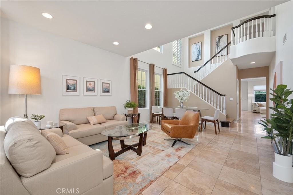 living area with recessed lighting, stairs, a high ceiling, and visible vents