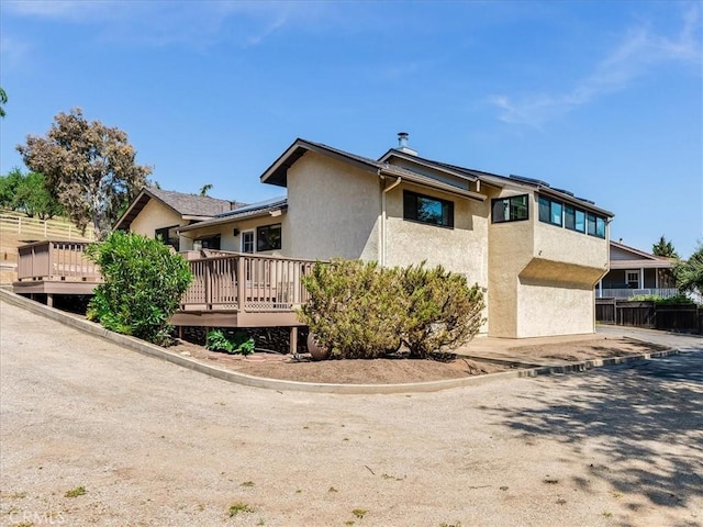 view of home's exterior featuring a deck, fence, and stucco siding