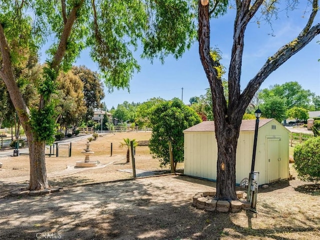 view of property's community featuring an outdoor structure, fence, and a shed
