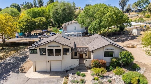 view of front of property featuring concrete driveway, an attached garage, roof with shingles, and stucco siding