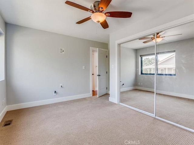 unfurnished bedroom with visible vents, baseboards, a closet, and light colored carpet