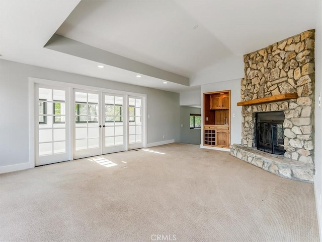 unfurnished living room featuring a fireplace, carpet floors, french doors, baseboards, and vaulted ceiling