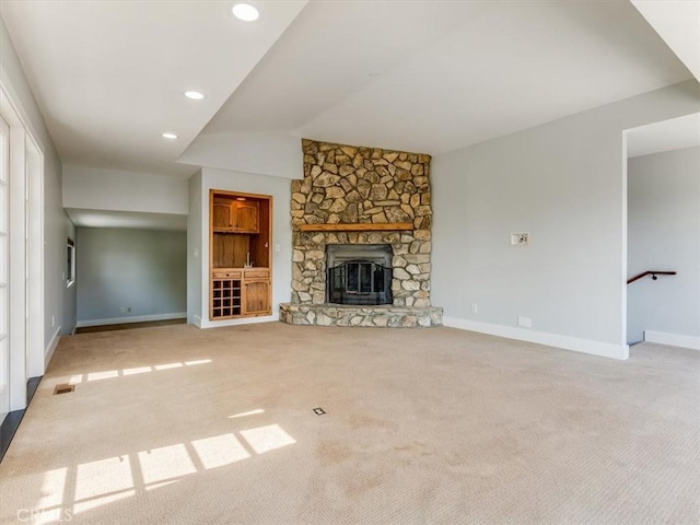 unfurnished living room with baseboards, carpet floors, lofted ceiling, and a stone fireplace