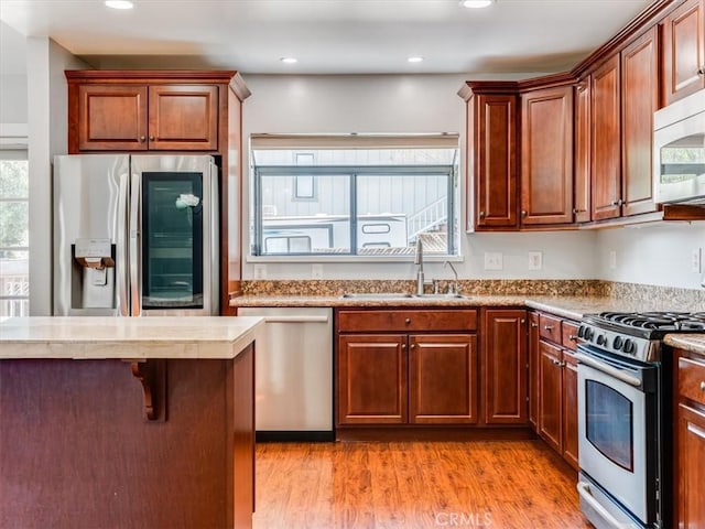kitchen featuring a sink, stainless steel appliances, light wood-type flooring, and a healthy amount of sunlight