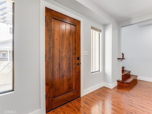 foyer with stairway, baseboards, and wood finished floors