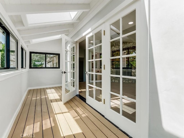 unfurnished sunroom with a skylight, french doors, and beam ceiling