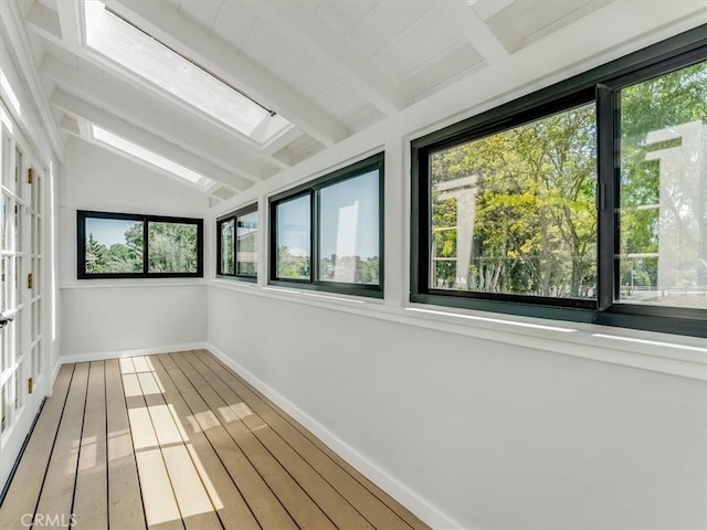 unfurnished sunroom featuring vaulted ceiling with skylight, baseboards, and wood finished floors