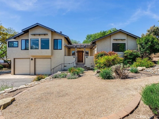 split level home with a garage, stucco siding, and driveway