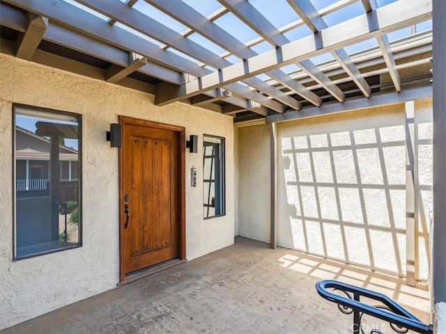 property entrance featuring stucco siding and a pergola