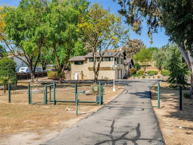 exterior space featuring a gate, fence private yard, a garage, aphalt driveway, and stucco siding