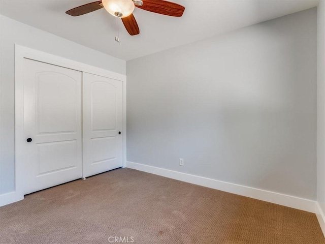 unfurnished bedroom featuring baseboards, ceiling fan, light carpet, and a closet