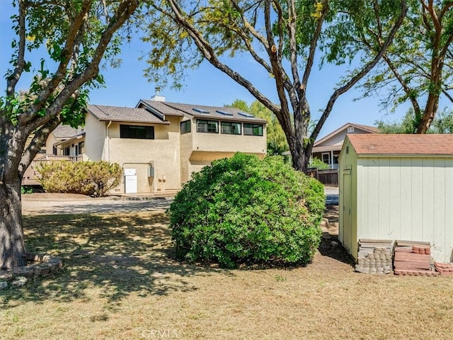 view of side of property with an outbuilding, stucco siding, and a shed