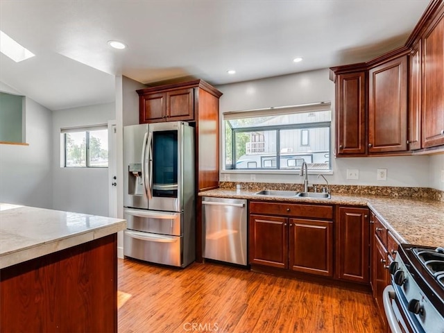 kitchen featuring stainless steel appliances, recessed lighting, a sink, and light wood finished floors