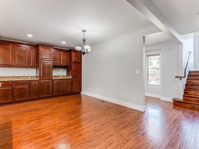 unfurnished living room with a notable chandelier, recessed lighting, baseboards, wood finished floors, and stairway