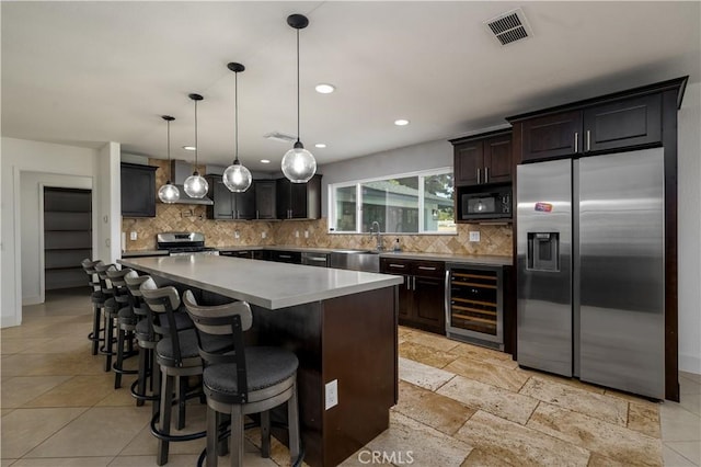 kitchen featuring wine cooler, a center island, visible vents, backsplash, and appliances with stainless steel finishes