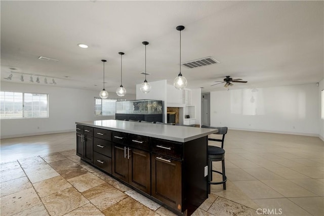 kitchen with a breakfast bar, open floor plan, visible vents, baseboards, and light countertops