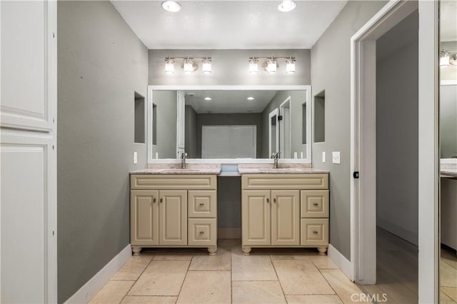 full bathroom with double vanity, baseboards, and a sink