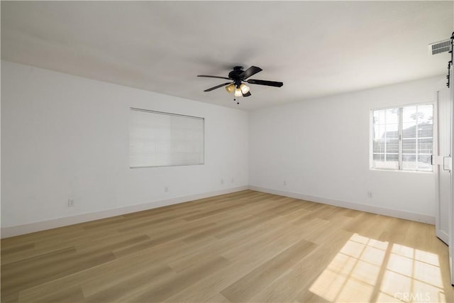 unfurnished room with visible vents, a ceiling fan, light wood finished floors, and baseboards