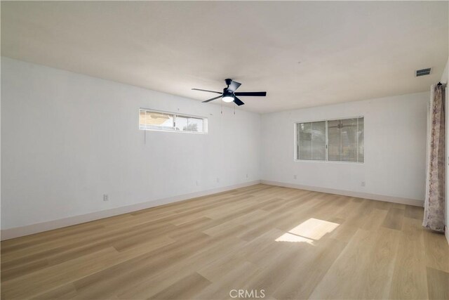 empty room with light wood-style floors, baseboards, ceiling fan, and visible vents