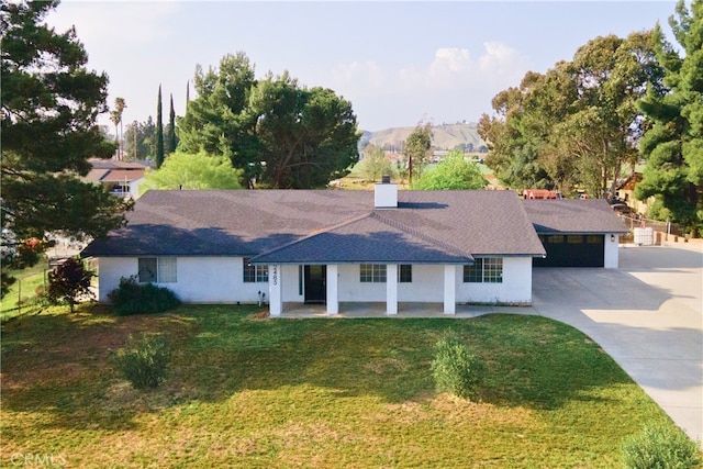 2485 W Westward Ave, Banning, CA 92220 - ranch-style house with concrete driveway, a front yard, a chimney, covered porch, and an attached garage