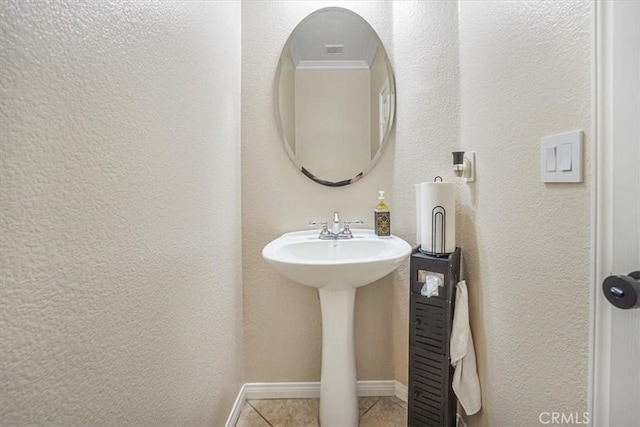 bathroom featuring crown molding, baseboards, a textured wall, and tile patterned floors