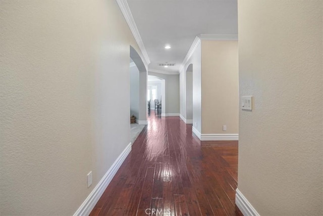 hall with crown molding, wood-type flooring, arched walkways, baseboards, and visible vents