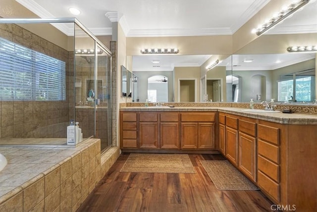 bathroom with double vanity, a sink, wood finished floors, and a stall shower