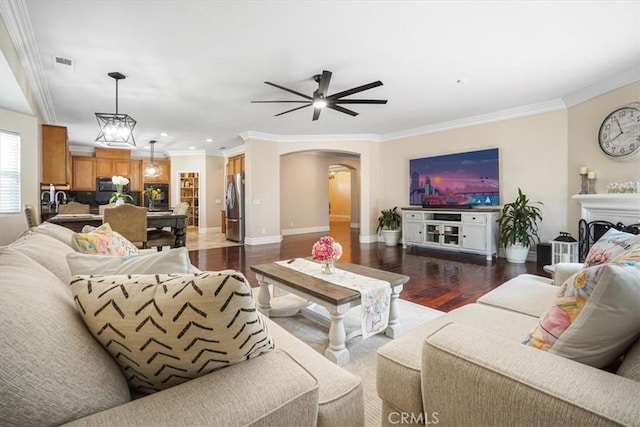 living room with arched walkways, ceiling fan, visible vents, and wood finished floors