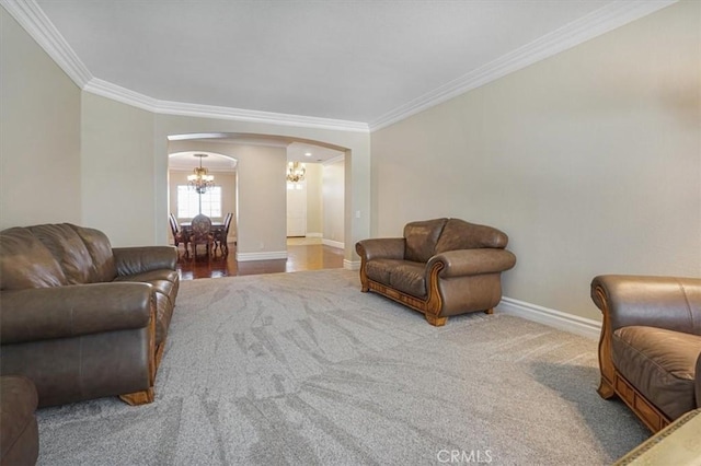 living area featuring arched walkways, baseboards, carpet floors, a notable chandelier, and ornamental molding