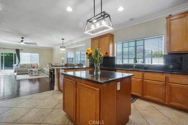 kitchen featuring brown cabinets, light tile patterned flooring, a sink, and a center island