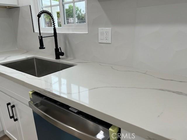 10065 Tudor Ave, Montclair, CA 91763 - interior details featuring stainless steel dishwasher, white cabinets, light stone counters, and a sink