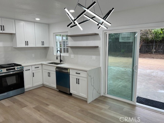 10065 Tudor Ave, Montclair, CA 91763 - kitchen with stainless steel gas stove, dishwasher, a sink, white cabinets, and light wood-style flooring
