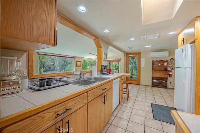 kitchen with visible vents, white appliances, a wall mounted air conditioner, tile countertops, and a sink