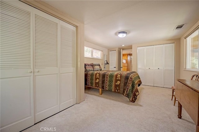 bedroom featuring visible vents, carpet floors, and two closets