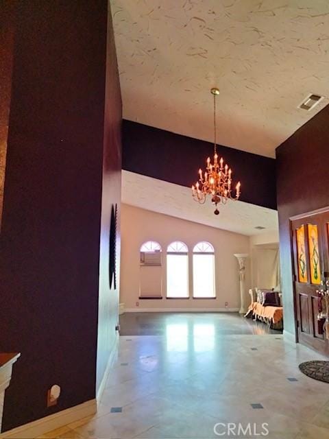 entryway featuring an inviting chandelier, baseboards, visible vents, and high vaulted ceiling