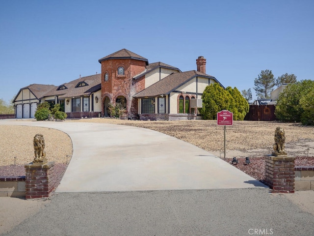view of front of home featuring curved driveway, an attached garage, fence, and brick siding
