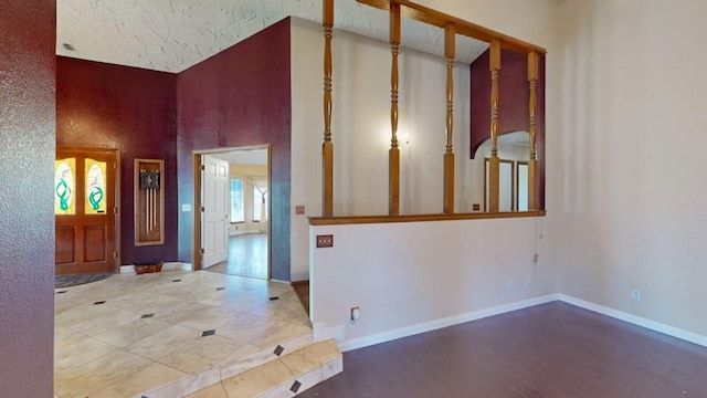 hallway with baseboards, tile patterned floors, and a high ceiling