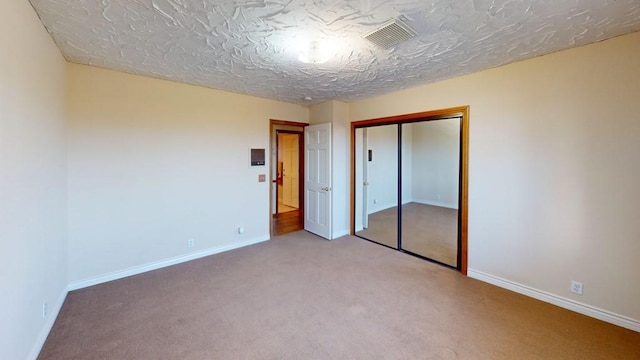 unfurnished bedroom with carpet flooring, baseboards, visible vents, and a closet