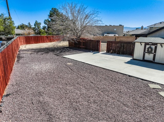 view of yard with a fenced backyard, a storage unit, and a patio area