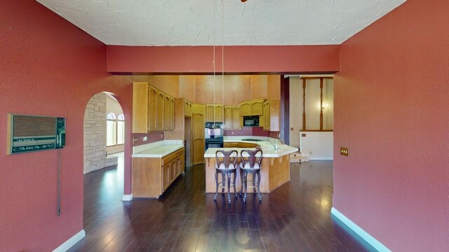 kitchen with a peninsula, baseboards, dark wood-style floors, light countertops, and black appliances
