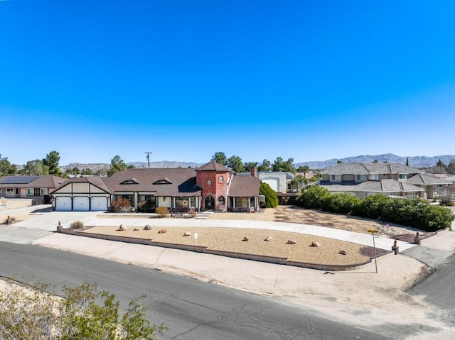 english style home featuring concrete driveway, a residential view, a mountain view, and a garage